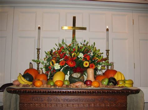 a table topped with fruit and flowers next to a cross