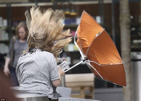 Inside out: A woman tries to shelter from the wind and rain with her ...