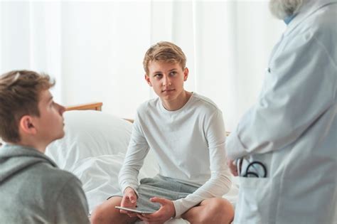 Premium Photo | Teenage young patient is sitting crosslegged on a hospital bed during ...