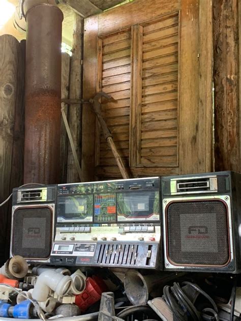 an old radio sitting on top of a pile of junk next to a wooden building