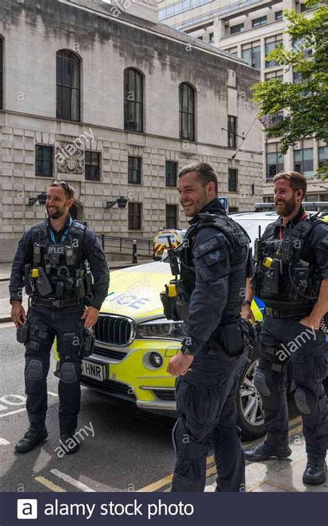 City of London armed police officers take a break and stand in conversation next to parked ...