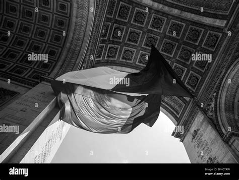 French flag waving under Arc de Triomphe in honor of VE day. Paris, France. Black white historic ...