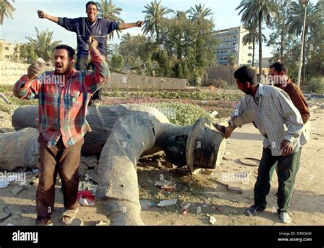 Iraqis are cheering in front of a fallen statue of Saddam Hussein on 12 April 2003 in Baghdad ...