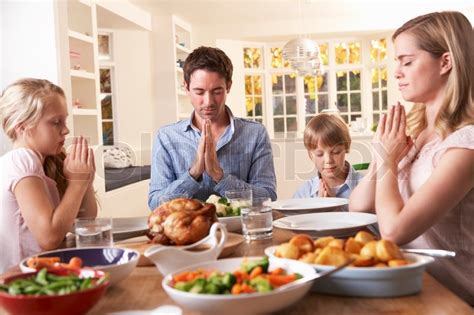 Family Saying Prayer Before Eating Roast Dinner | Stock Photo | Colourbox