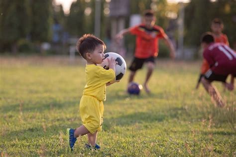 Premium Photo | Little boy playing football in the field