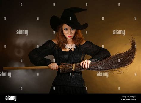 Halloween witch with broom on dark background Stock Photo - Alamy