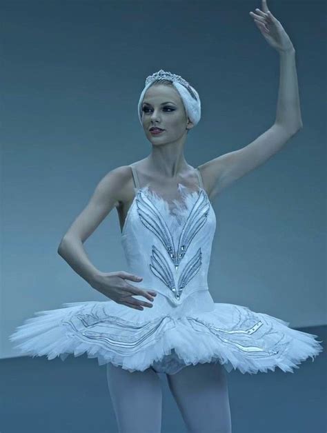 a ballerina in white tutu and headband posing for the camera with her hand up