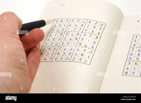 Su doku or Sudoku game on a book with a hand and a pen Stock Photo ...