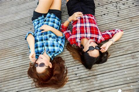 Two Woman Wearing Blue and Red Sport Shirts and Sunglasses Lying on Brown Surface · Free Stock Photo