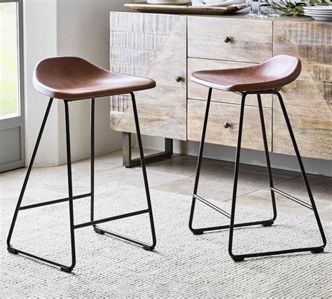 two brown barstools sitting next to each other in front of a dresser and window