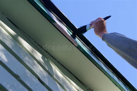 A Person is Up a Ladder Painting a Bargeboard, the Paintbrush is Set Against a Blue Sky Stock ...