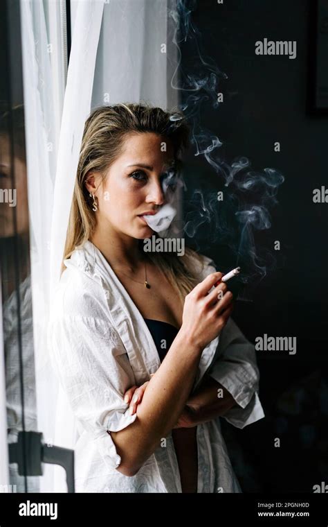 Young woman smoking cigarette at home Stock Photo - Alamy