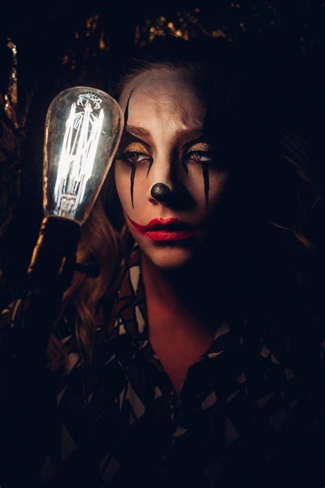 a woman with makeup on her face holding a light bulb