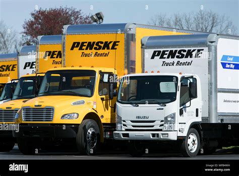 A logo sign and rental trucks outside of a facility occupied by Penske Truck Leasing in Reading ...