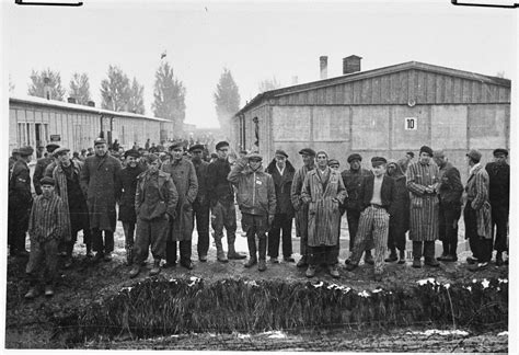 Group portrait of survivors standing next to the moat in the Dachau concentration camp following ...