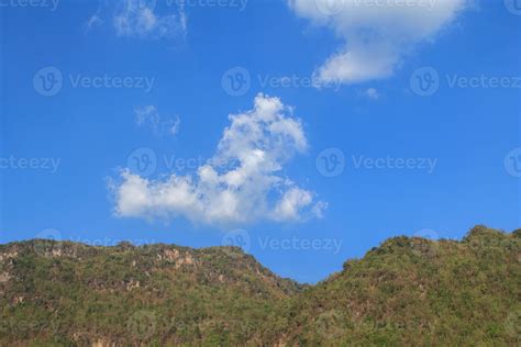 Clouds like poodle dogs float in the air in the clear sky and warm sunlight during the day and ...