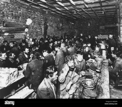 A large group of Russian workers eating whilst sitting at long wooden tables in their canteen ...