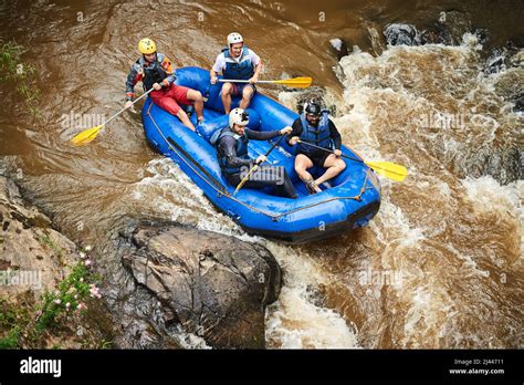 Through the rapids. High angle shot of a group of young friends white water rafting Stock Photo ...