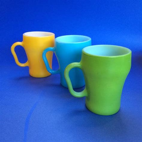 three different colored coffee mugs sitting next to each other on a ...
