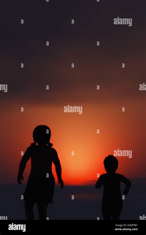 Silhouette of two children running towards the sunset Stock Photo - Alamy