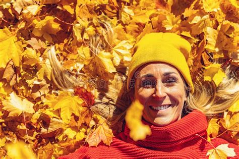 Woman Smiling Lying on Yellow and Red Leaves at Park, View from Above. Top View of Playful Woman ...