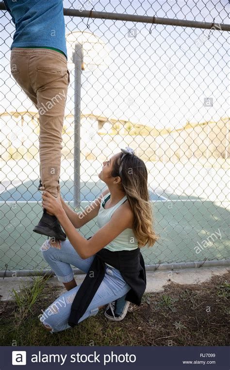 Latinx young woman lifting man over fence at tennis court Stock Photo - Alamy