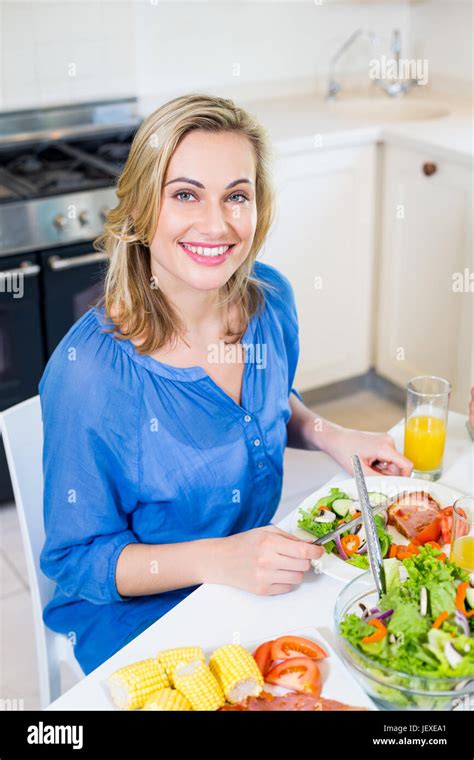 Young woman sitting at dining table smiling Stock Photo - Alamy