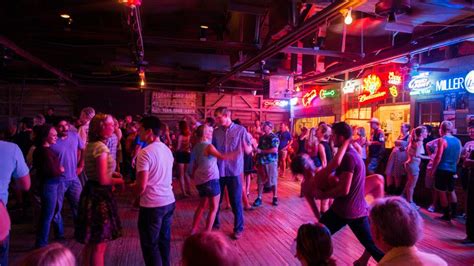 a group of people dancing in a crowded room with neon signs on the ...