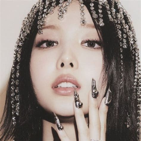 a woman with black and silver nail polish holding her hand up to her face while wearing headdress