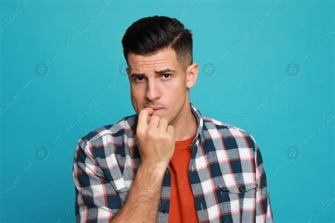 Man biting his nails on light blue background. Bad habit: Stock Photo | Download on Africa ...