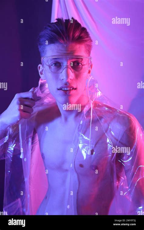 Stylish young man wearing clear coat and glasses in neon lights Stock Photo - Alamy