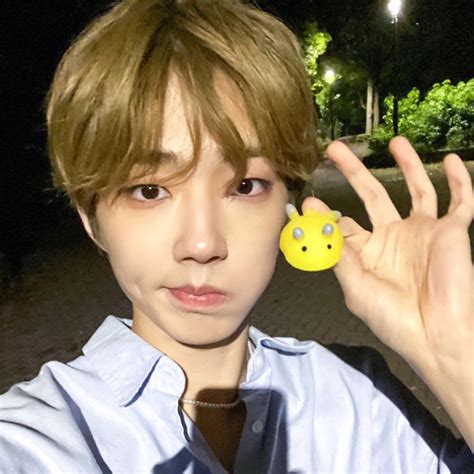 a young man holding up a yellow smiley face brooch in front of his face