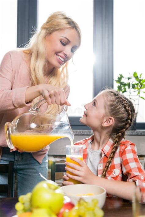 Mother Pouring Orange Juice for Daughter on Breakfast while Father ...