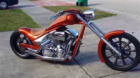 an orange and silver motorcycle parked on the side of a road next to a ...