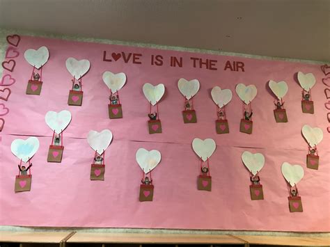 a pink bulletin board with hearts attached to it and the words love is in the air