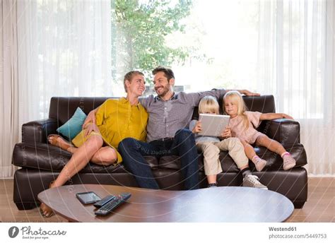 Family sitting on couch at home using tablet - a Royalty Free Stock ...