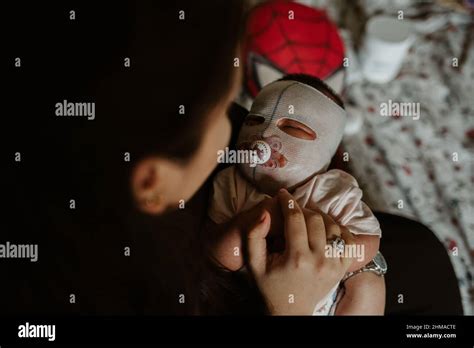 Mother looking at her newborn girl with eczema face mask Stock Photo - Alamy