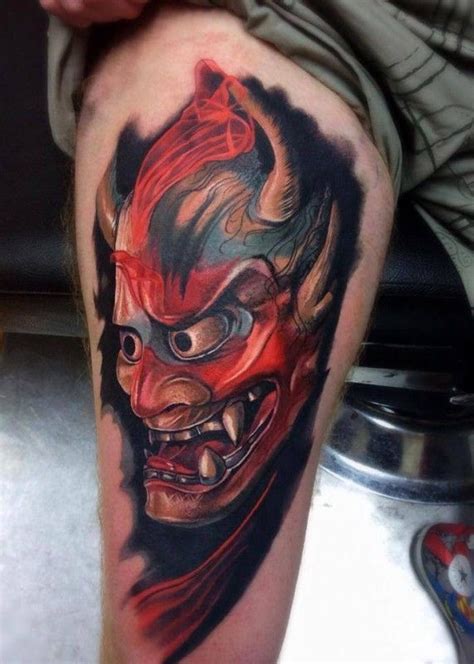 a man's leg with a tattoo on it and an evil demon face in the center