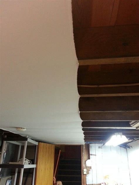 It's hard to see but you can cover your ugly basement ceiling with cheap white fabric and a ...