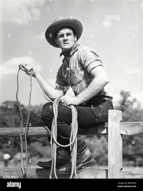 Cowboy holding lasso sitting on fence Stock Photo - Alamy