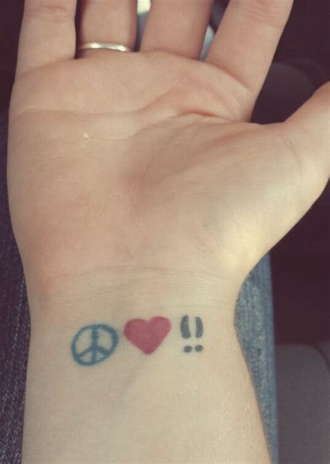 a person with a peace sign and heart tattoo on their wrist