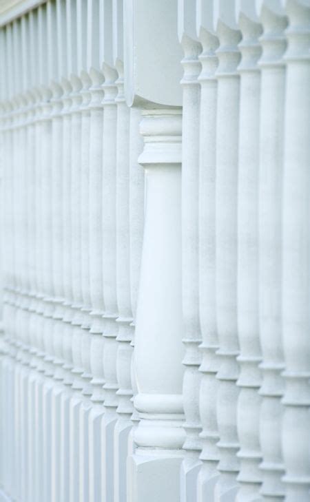Wooden porch railing with white balusters and center post in shade | Freestock photos