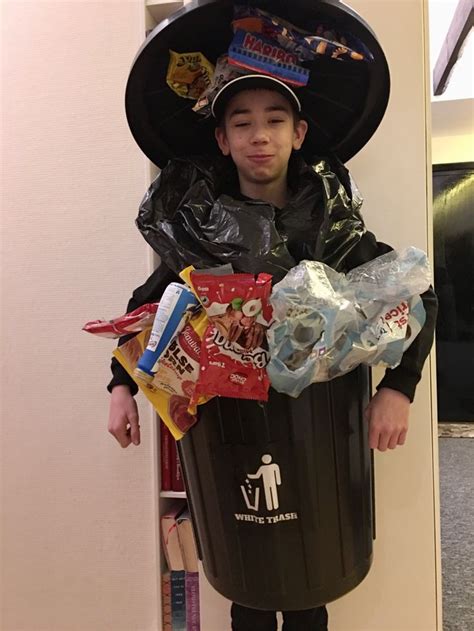 a young boy dressed up as a trashcan and wearing a hat with snacks in it