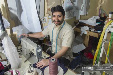 Male tailor working on sewing machine in workshop with tailoring ...