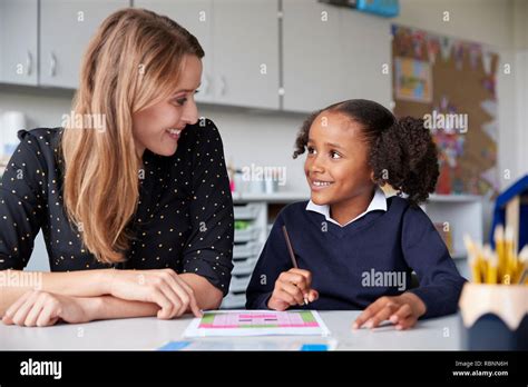 Young female primary school teacher working one on one with a ...