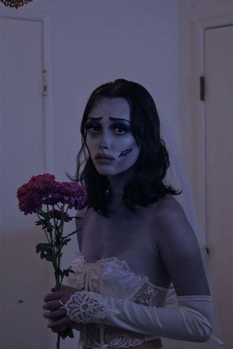 a woman with makeup on her face and arm holding flowers in front of the camera