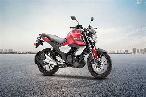 a red and white motorcycle is parked on the street in front of a cityscape