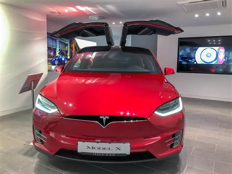 Elektroauto laden: Tesla Model 3 mit einem Typ 2 Ladestecker, tankt Sonnenenergie vor dem Aldi ...