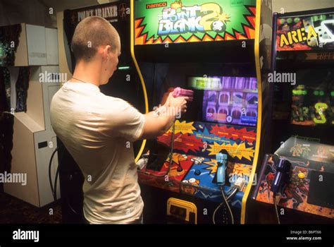 Teen boy plays arcade shooting game Stock Photo - Alamy