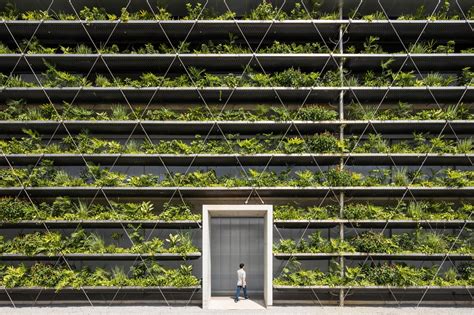 Tropical Plants Sprout from the Mesh Facade of an Open-Air Factory in ...